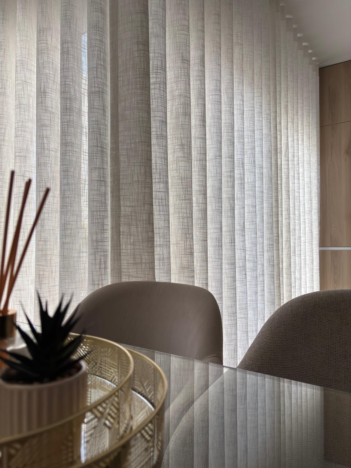 Pormenor de cortinado de onda em linho junto a uma mesa de jantar
