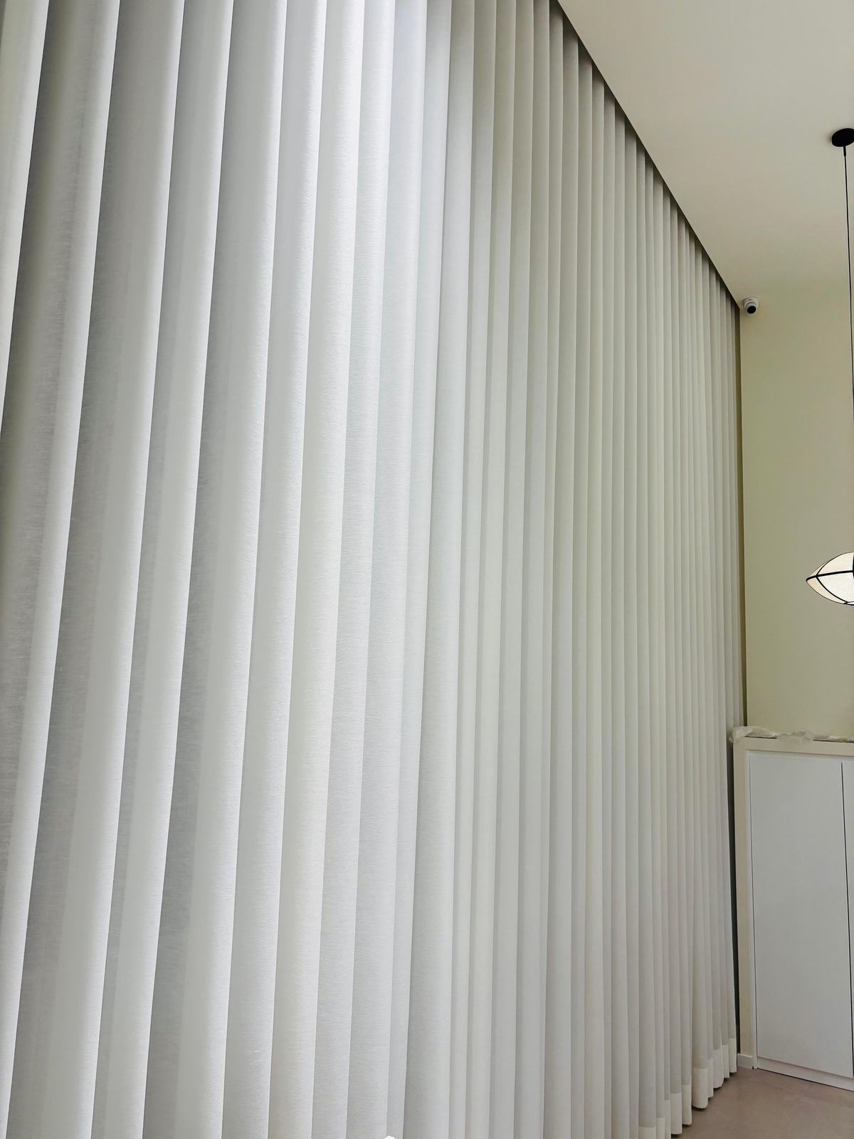 Pormenor das pregas regulares de um cortinado de onda em tecido claro