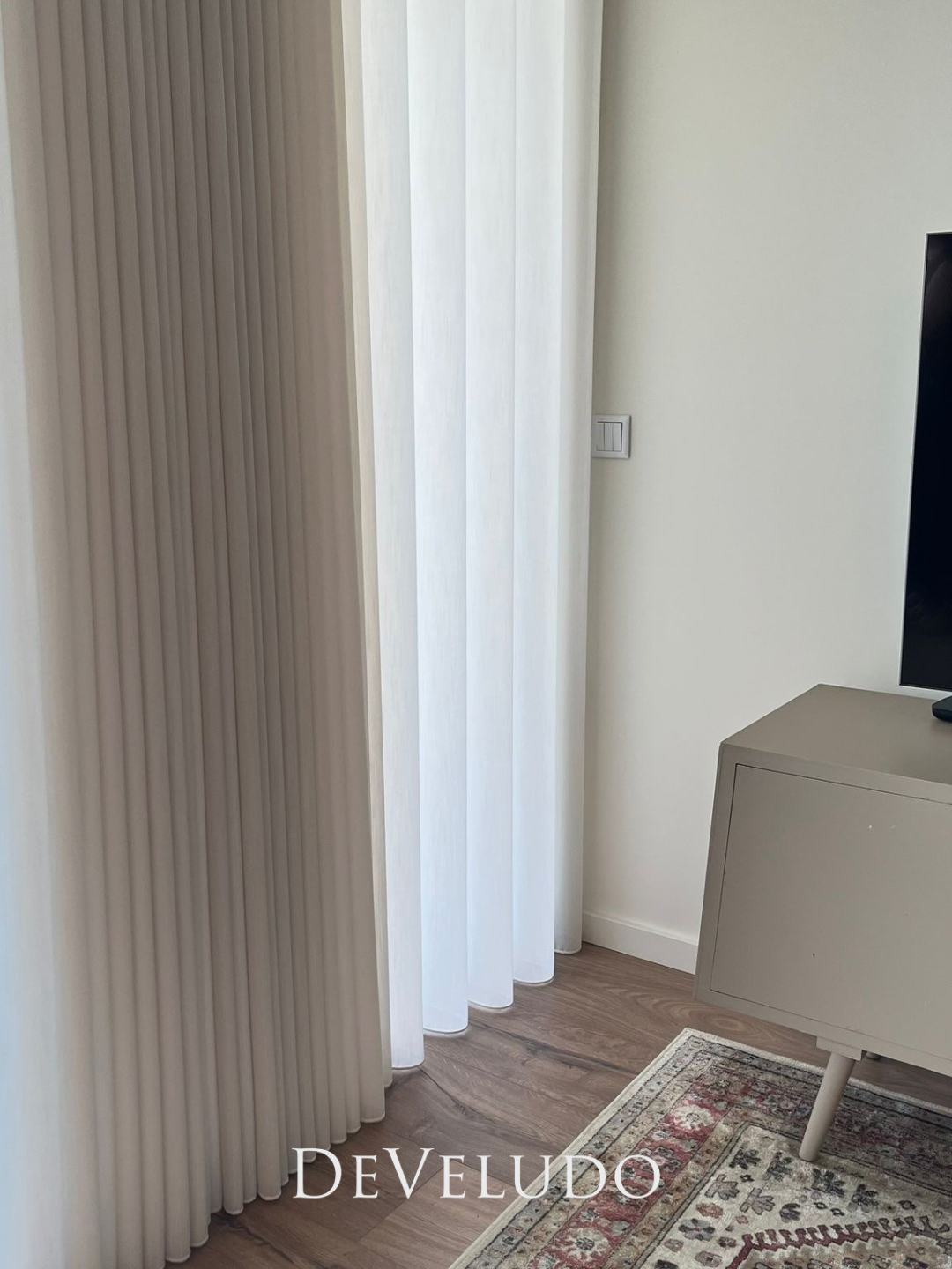 Cortinado de onda em tecido texturado, com um tapete de padrão clássico no chão