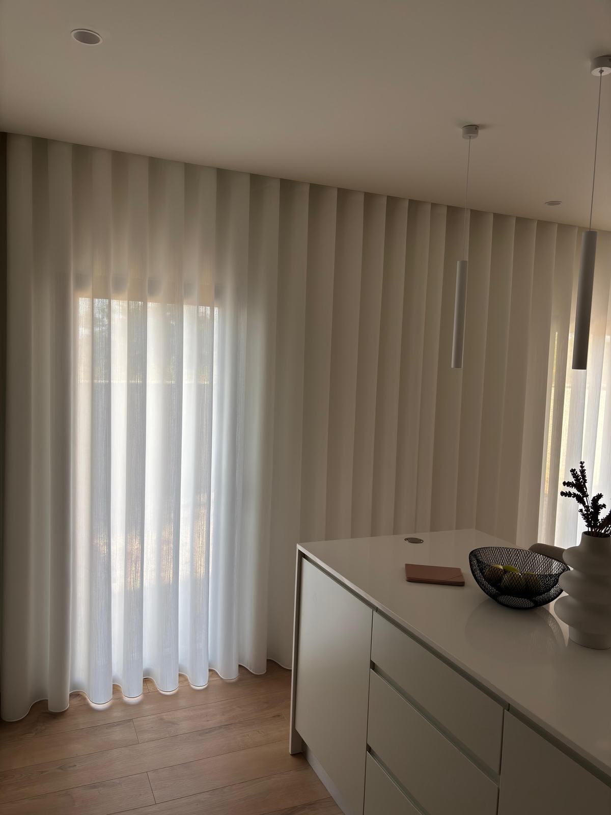Cozinha com ilha e cortinado de onda a vestir a janela