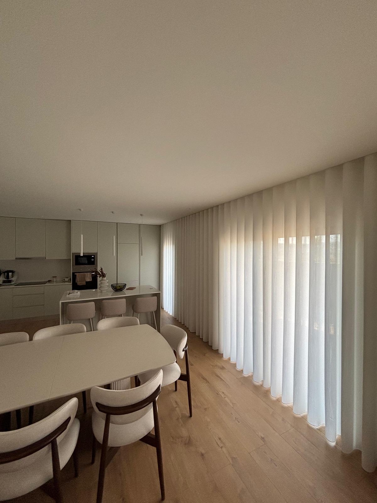 Cozinha aberta para a sala de jantar, com cortinados de onda ao fundo